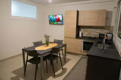 a kitchen with a table and chairs and a television on the wall at Casa d'a-mare in Terrasini