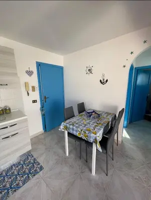 a dining room with a table and chairs and a blue door at Casa Scirocco in Balestrate