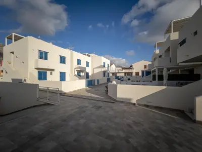 a row of white buildings with a blue sky in the background at Savoia's apartments in San Vito lo Capo