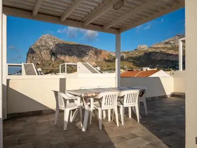 a table and chairs on a balcony with a view of mountains at Savoia's apartments in San Vito lo Capo