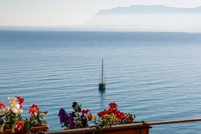 a sail boat in the water with flowers in front at Hotel Punta Nord Est in Castellammare del Golfo
