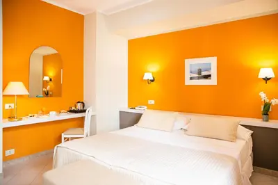 a bedroom with an orange wall and a bed at Hotel Al Madarig in Castellammare del Golfo