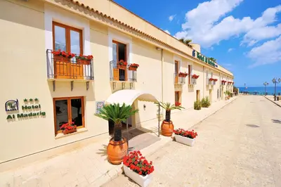 a building with potted plants on a street at Hotel Al Madarig in Castellammare del Golfo