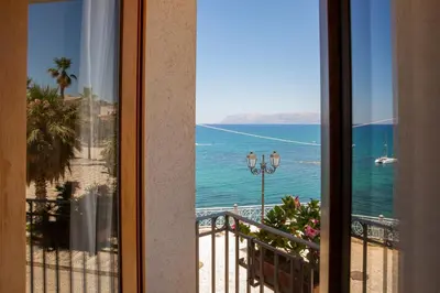 a room with a view of the ocean from a balcony at Hotel Al Madarig in Castellammare del Golfo