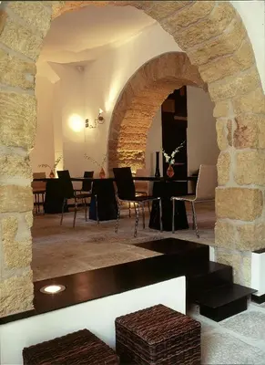 a room with a stone archway and tables and chairs at Hotel Cetarium in Castellammare del Golfo