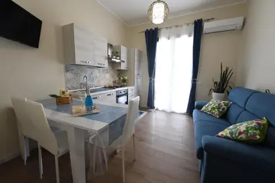 a kitchen and living room with a table and a blue couch at Terra Sinus Luxury apartment in Terrasini
