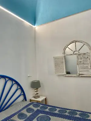 a bedroom with a blue bed and a mirror at Casa vacanze stella marina in Trappeto