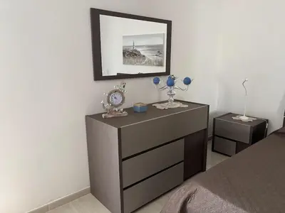 a bedroom with a dresser with a clock on it at Casa Maria Costa Blu in Isola delle Femmine