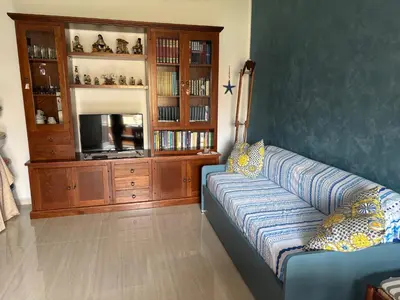 a living room with a blue couch and a tv at Casa Maria Costa Blu in Isola delle Femmine