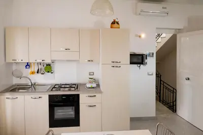 a kitchen with white cabinets and a sink and a refrigerator at Le Case di Katy in Castellammare del Golfo