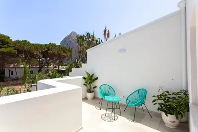 two chairs and a table on the balcony of a house at Zizha Suite sul mare - San Vito Lo Capo in San Vito lo Capo
