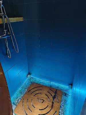 a blue tiled shower with a drain in a bathroom at Studio Sedie Volanti in Palermo