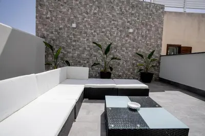 a patio with white benches and plants in front of a brick wall at B&B il Colibrì in San Vito lo Capo