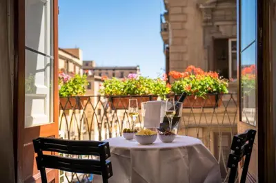 a table with wine glasses on a balcony at Ballaro' Hotel - Budget Room in Palermo