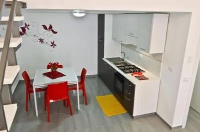 a kitchen with a table and red chairs and a stove at Casa vacanza Raggio di Sole in Castellammare del Golfo
