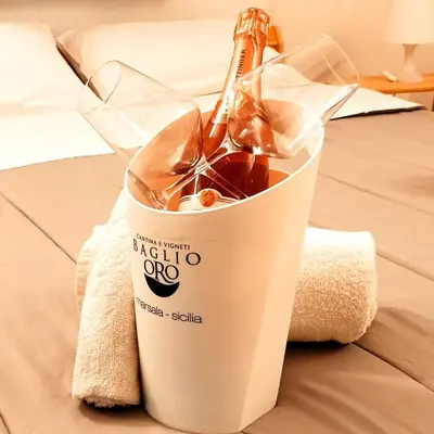 a bottle of wine in a cup on a bed at Ai Normanni in Palermo