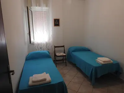 a room with two beds and a chair and a window at Leonardo in Capaci