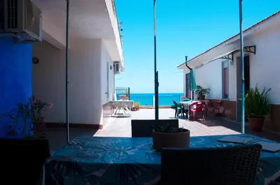 a table and chairs on a patio with a blue wall at Villetta Cicciuli in Altavilla Milicia
