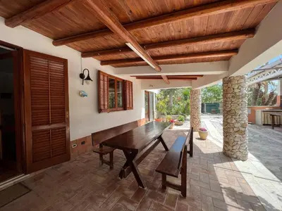 an outdoor dining room with a wooden table and chairs at Villa Barone in Castellammare del Golfo