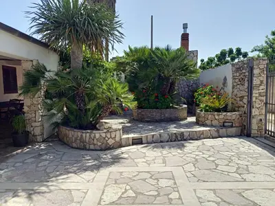 a courtyard with palm trees inront of a building at Villa Barone in Castellammare del Golfo