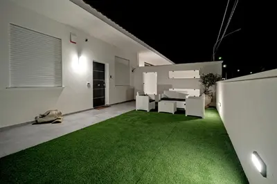 a living room with a green carpet and white furniture at AL BAYDA in Palermo