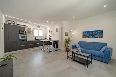 a living room with a blue couch and a kitchen at AL BAYDA in Palermo