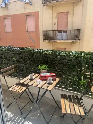 a table and chairs on a balcony with a green wall at Maqueda Suites in Palermo