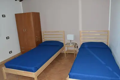 two beds in a room with blue sheets at Appartamento Casa Magnolia in San Vito lo Capo