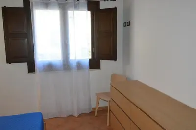 a bedroom with a window and a table and chair at Appartamento Casa Magnolia in San Vito lo Capo