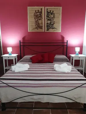 a bedroom with a bed with pink walls and two tables at CASA VACANZA DI VIA GIACALONE in Palermo