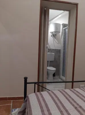 a bedroom with a bed and a bathroom with a toilet at CASA VACANZA DI VIA GIACALONE in Palermo