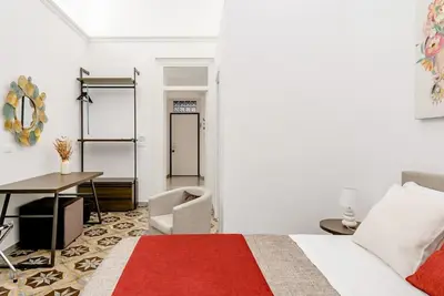 a bedroom with a bed and a table and a desk at Cortile Marconi Apartment in Palermo