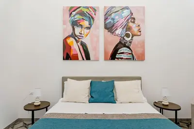 a bedroom with a bed with a painting on the wall at Cortile Marconi Apartment in Palermo