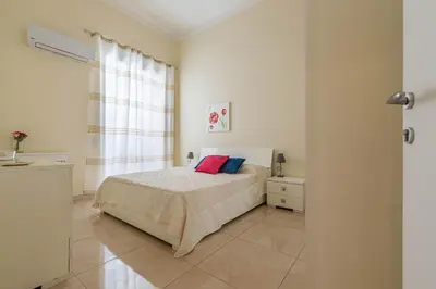 a white bedroom with a bed and a window at Olivella Apartment al Teatro Massimo by Wonderful Italy in Palermo