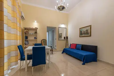 a living room with a table and a blue couch at Olivella Apartment al Teatro Massimo by Wonderful Italy in Palermo