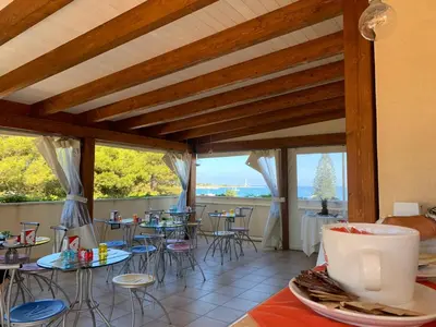 a room with tables and chairs and windows at Hotel Iride by Marino Tourist in San Vito lo Capo