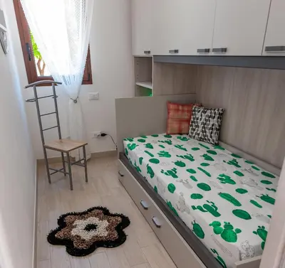 a small bedroom with a bed and a chair at AL BARONE in Scopello