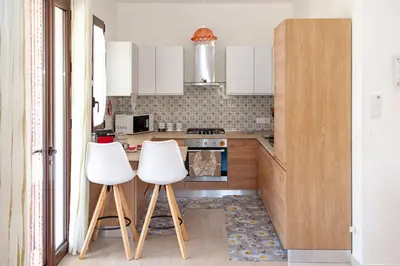 a kitchen with white cabinets and two white stools at AL BARONE in Scopello