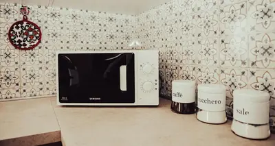 a microwave sitting on a counter with three coffee cups at AL BARONE in Scopello