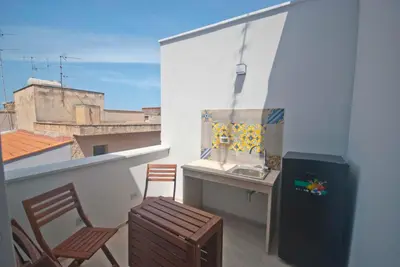 a balcony with a kitchen and a sink and chairs at GIADA in Castellammare del Golfo