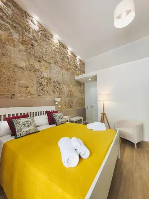 a bedroom with a yellow bed with towels on it at Dimora Carella Ai 5Venti in Palermo