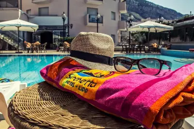 a pair of glasses sitting on a towel next to a swimming pool at Hotel Sirenetta in Isola delle Femmine