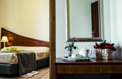 a bedroom with a bed and a table with a mirror at Hotel Sirenetta in Isola delle Femmine