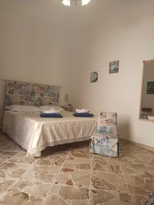 a bedroom with a bed and a chair in it at NARDINA HOUSE in Castellammare del Golfo