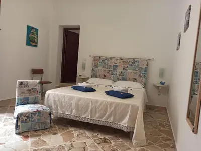 a bedroom with a bed with blue pillows on it at NARDINA HOUSE in Castellammare del Golfo