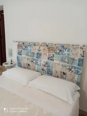 a bed with a collage of photos on the headboard at NARDINA HOUSE in Castellammare del Golfo
