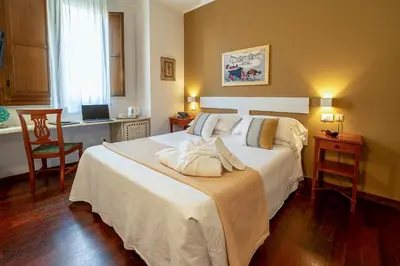 a bedroom with a bed and a desk with a laptop at Hotel Vecchio Borgo in Palermo