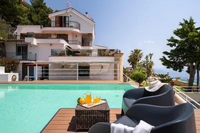 a villa with a swimming pool in front of a house at Villa vista mare con piscina privata a Mondello in Palermo