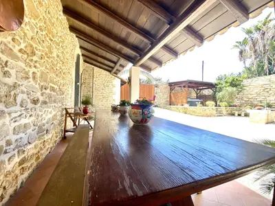 a wooden table in a patio with a stone wall at Baglio Giganti in Alcamo