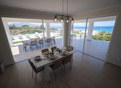 a dining room with a table and chairs and a view of the ocean at Villa Lombardo Luxury in Balestrate